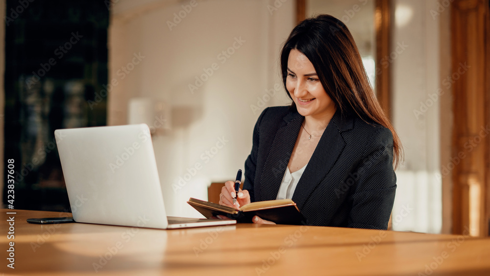 A woman of European appearance is typing on a laptop computer manager. Writes down ideas for a new project or startup. . Business clothing. Workplace in a coworking office for rent for an hour. A woman of European appearance is typing on a laptop computer manager. Writes down ideas for a new project or startup. . Business clothing. Workplace in a coworking office for rent for an hour.