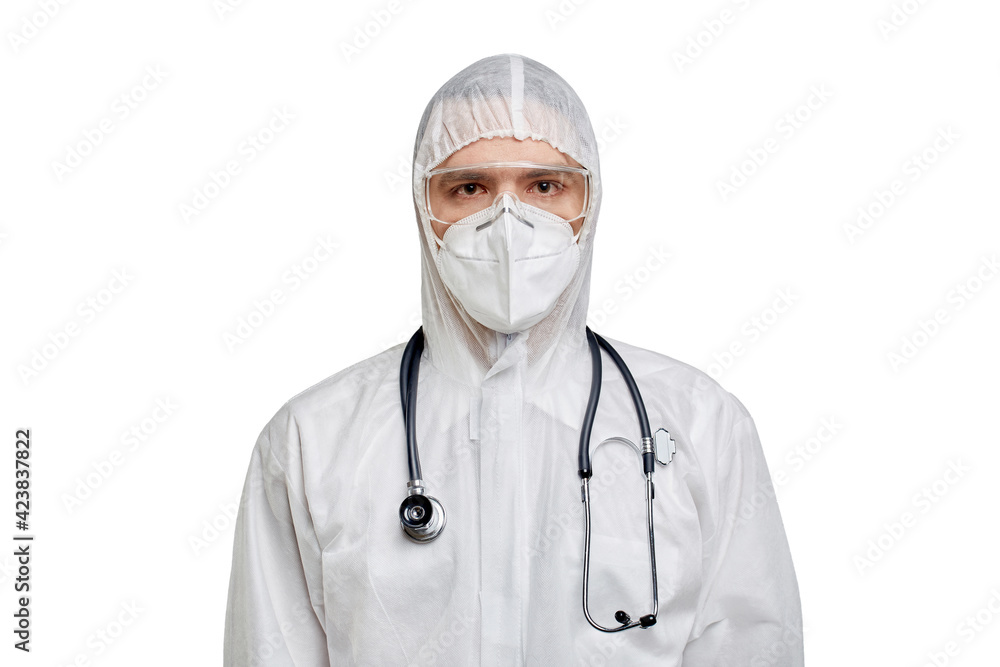 The doctor is a man in PPE and safety glasses and looks at the camera. Protection against coronavirus. White isolated background. The doctor is a man in PPE and safety glasses and looks at the camera. Protection against coronavirus. White isolated background.