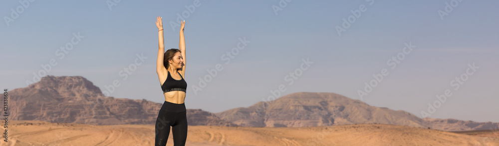 A thin athletic girl takes a break between classes on the background of mountains in the early morning A thin athletic girl takes a break between classes on the background of mountains in the early morning