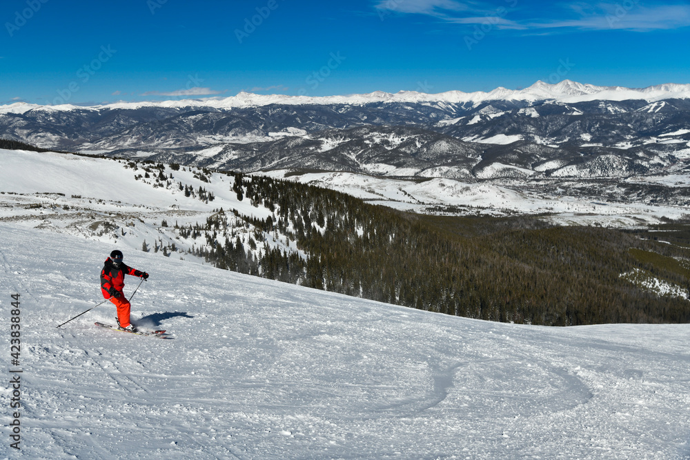Man wearing bright red suit skiing on snowy backcountry bowl area. Extreme winter sports. Breckenridge, Colorado at Emperial bowl area Man wearing bright red suit skiing on snowy backcountry bowl area. Extreme winter sports. Breckenridge, Colorado at Emperial bowl area