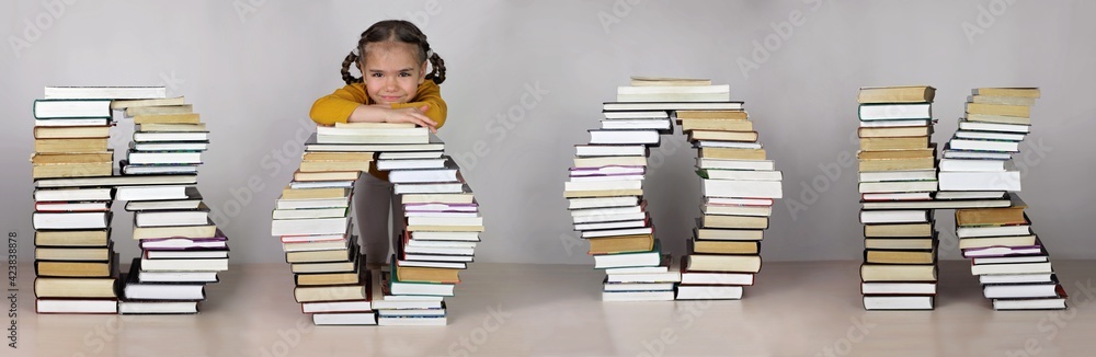 Smart cute girl and huge letters with a lot of books forming a word book, studio shot, study and education concept Smart cute girl and huge letters with a lot of books forming a word book, studio shot, study and education concept