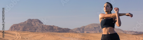 A thin athletic girl takes a break between classes on the background of mountains in the early morning © Mountains Hunter