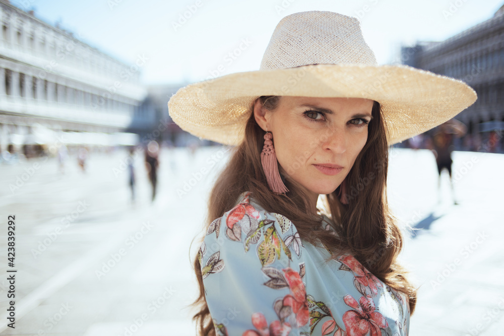 Portrait of young solo traveller woman in floral dress with hat