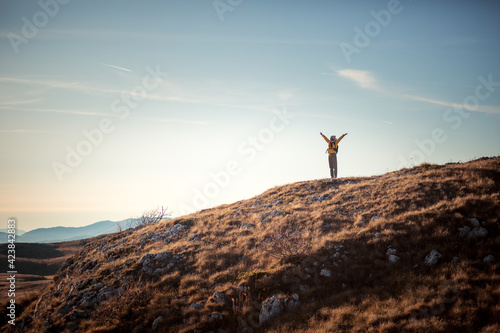 Successful woman raising hands on mountain