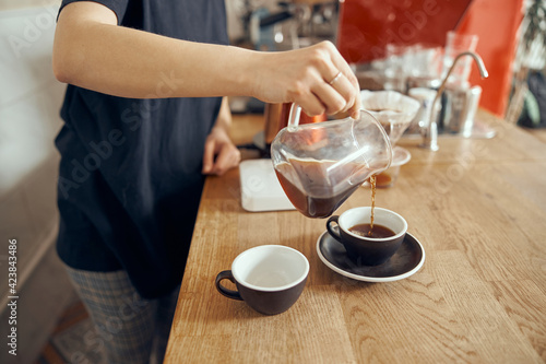 Professional barista photo of barista at counter in cafe pouring filter coffee in cup. Alternative ways of brewing coffee. Coffee shop concept