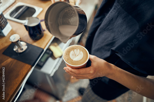 Barista making cappuccino, bartender preparing coffee drink. Coffee cup with latte art