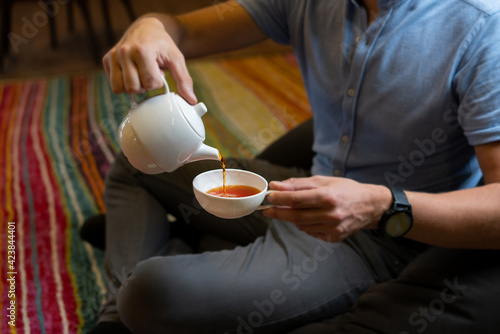 Man pouring tea into white cup
