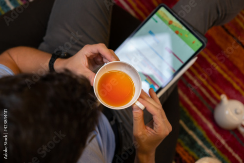 Man drinking tea near tablet