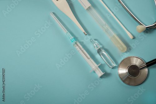 Medical concept  top view. Medical test for covid 19. Medical supplies  thermometer  stethoscope  syringe  ampoule with medicine for and test on a blue background. Place for your text. Banner