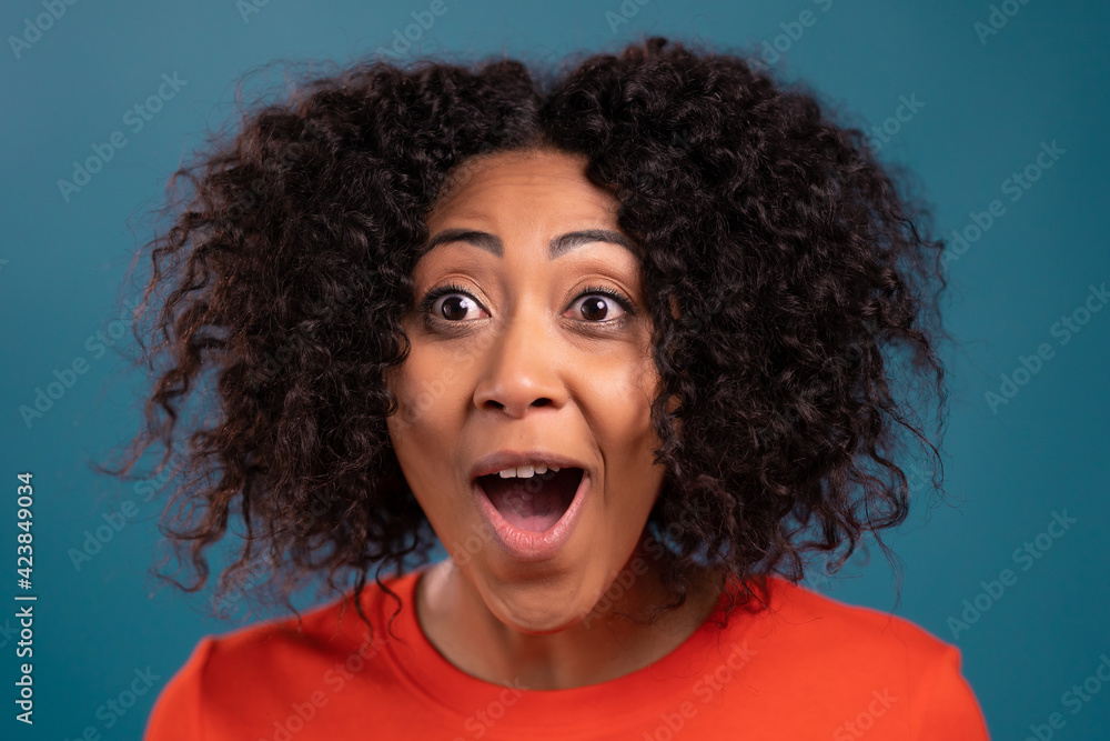 African woman is very glad, she screaming WOW loud. Concept of sales, profitable offer. Excited happy lady on blue studio background. African woman is very glad, she screaming WOW loud. Concept of sales, profitable offer. Excited happy lady on blue studio background.
