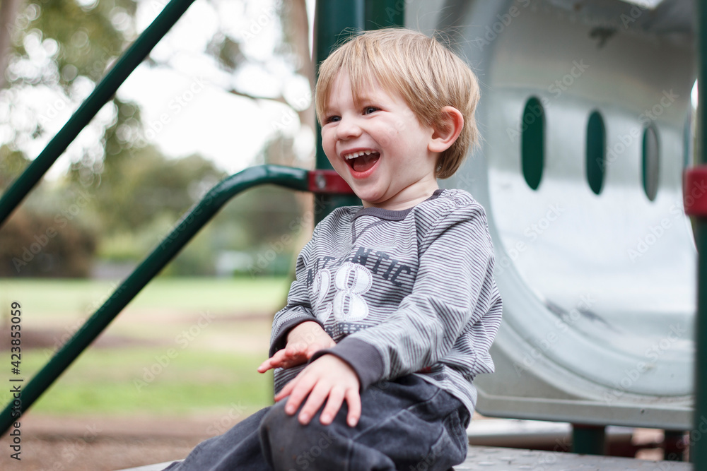 Toddler boy laughing at top of playground equipment Toddler boy laughing at top of playground equipment