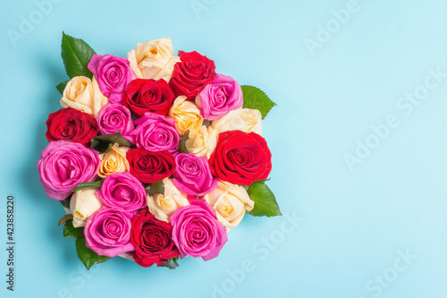 Composition of fresh multicolored roses on ceramic stand