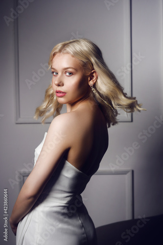 Gorgeous blonde in a white wedding dress. Woman with makeup, styling and silver earrings. The bride is beautiful. The model looks into the camera. Free Download Gorgeous blonde in a white wedding dress. Woman with makeup, styling and silver earrings. The bride is beautiful. The model looks into the camera. - GFXLoad