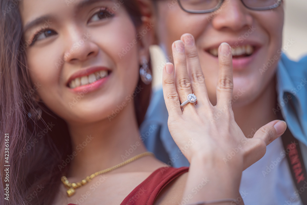 Newly engaged girl and fiance in the background. Fiancee Love and an elegant wedding white gold ring concept Newly engaged girl and fiance in the background. Fiancee Love and an elegant wedding white gold ring concept