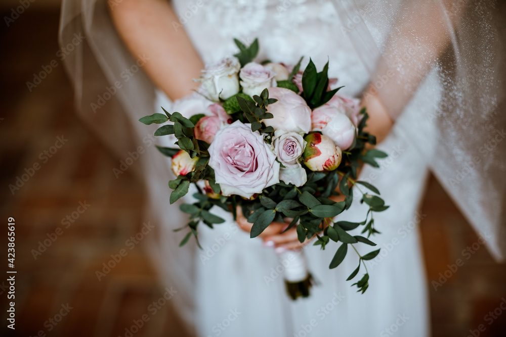 Newlywed bride holding beautiful peony wedding flowers in hands