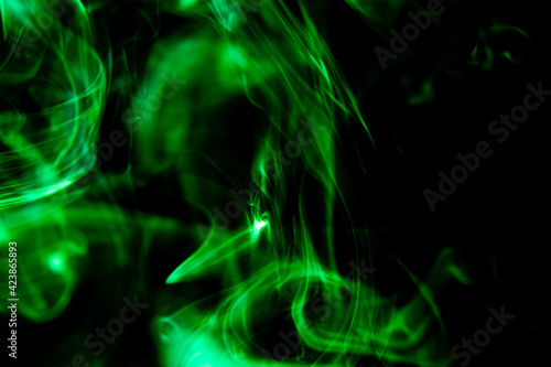 An abstract photograph of light green smoke on a black background. Creative smoke photography design.