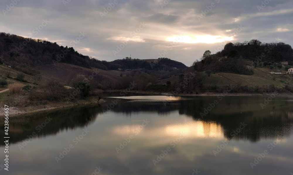 Verdi colline dell’Appennino marchigiano si riflettono al tramonto nelle acque del lago