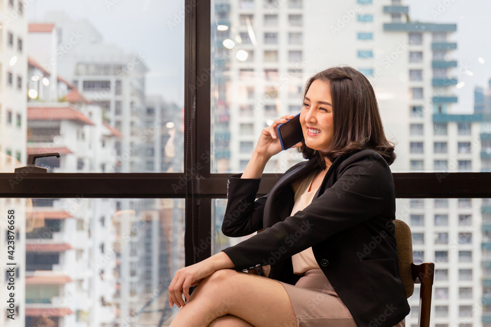 Smiling businesswoman using phone in office, business woman talking smartphone, female entrepreneur using cellphone in modern office Smiling businesswoman using phone in office, business woman talking smartphone, female entrepreneur using cellphone in modern office
