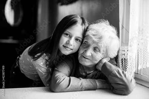 Little girl hugs her grandmother. Black and white portrait.