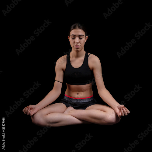 Young woman doing fitness exercise training isolated on the black background. Square shot.