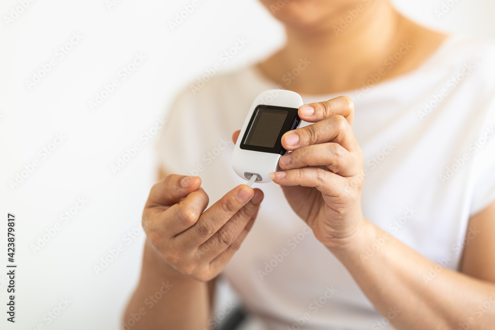 Close up of woman hands using Glucose meter on finger to check blood sugar level. Use as Medicine, diabetes, glycemia, health care and people concept.