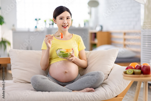 Asian pregnant woman eating salad