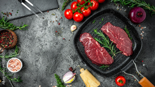 raw rump steak on pan on dark concrete background with spices salt and pepper. banner, menu recipe place for text, top view