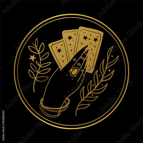 Graceful female hand of a gypsy woman holds tarot cards. Round gold icon on a black background. The concept of divination, witchcraft, fate, card game. Vector illustration isolated on background.