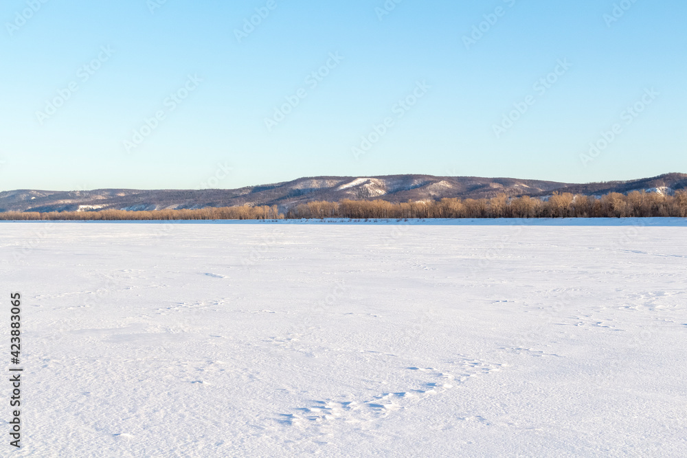 The surface of a wide frozen river and the opposite bank in the distance. The surface of a wide frozen river and the opposite bank in the distance.