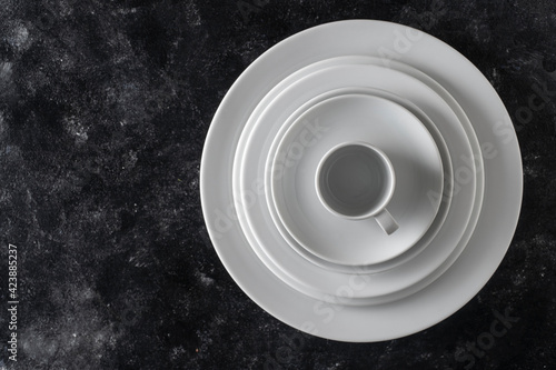 Many white empty plate and cup on black background, close up