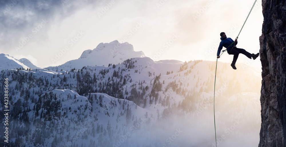 Epic Adventurous Extreme Sport Composite of Rock Climbing Man Rappelling from a Cliff. Mountain Landscape Background from British Columbia, Canada. Concept: Explore, Hike, Adventure, Lifestyle Epic Adventurous Extreme Sport Composite of Rock Climbing Man Rappelling from a Cliff. Mountain Landscape Background from British Columbia, Canada. Concept: Explore, Hike, Adventure, Lifestyle