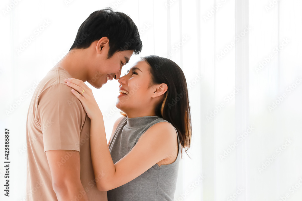 Portrait shot of cute smiling young Asian lover couple standing and passionate kissing together in the bedroom at weekends. Boyfriend and girlfriend sharing an intimate loving moment at home Portrait shot of cute smiling young Asian lover couple standing and passionate kissing together in the bedroom at weekends. Boyfriend and girlfriend sharing an intimate loving moment at home
