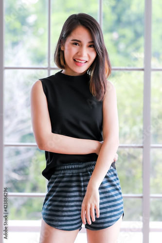 Portrait shot of a cute smiling Asian woman with a stylish straight hairstyle in black clothes standing and looking at the camera