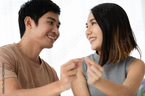 Cute smiling young Asian lover couple in casual clothes, showing a golden engagement rings together. Love and marraigek concept.
