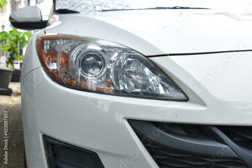old and blurred headlight surface as a result of weather condition and aging of a white car © Jiggo_Putter