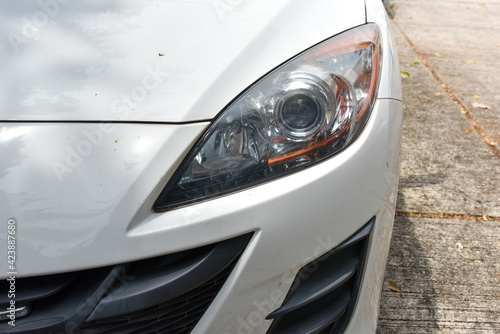 old and blurred headlight surface as a result of weather condition and aging of a white car © Jiggo_Putter