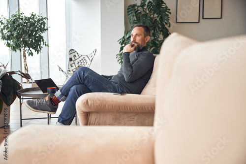 Happy adult caucasian man is sitting in a lounge zone and chilling