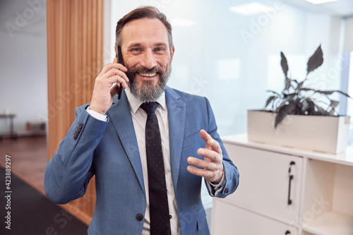 Happy adult caucasian businessman using smarthopne in a modern stylish office