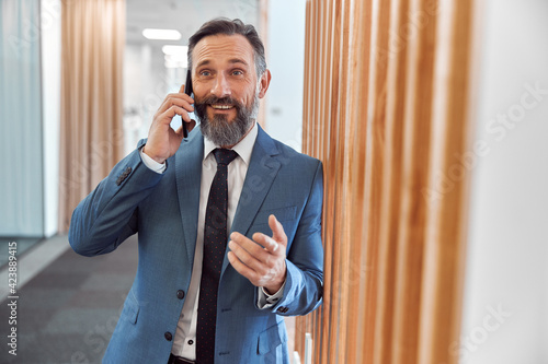 Happy adult caucasian businessman using smarthopne in a modern stylish office