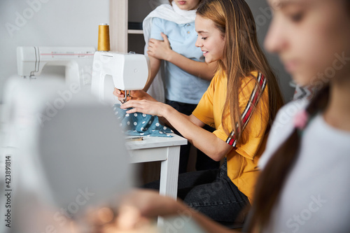 Cute little seamstresses sewing clothes in workshop