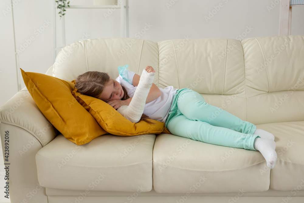 Child with a cast on a broken wrist or arm lying on a couch. Recovery and disease concept. Child with a cast on a broken wrist or arm lying on a couch. Recovery and disease concept.