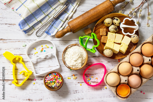 Baking background. Ingredients for Easter festive baking - flour, brown sugar, eggs, butter, confetti on rustic kitchen table.