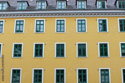 Yellow urban building façade with green windows