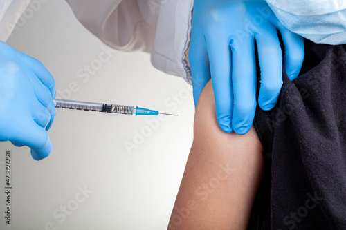 Tableau sur toile A health care professional wearing gloves and white coat is administering a childhood vaccine to a caucasian kid