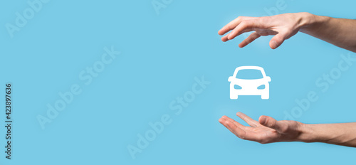 Male hand holding car auto icon on blue background. Wide banner composition.Car automobile insurance and collision damage waiver concepts