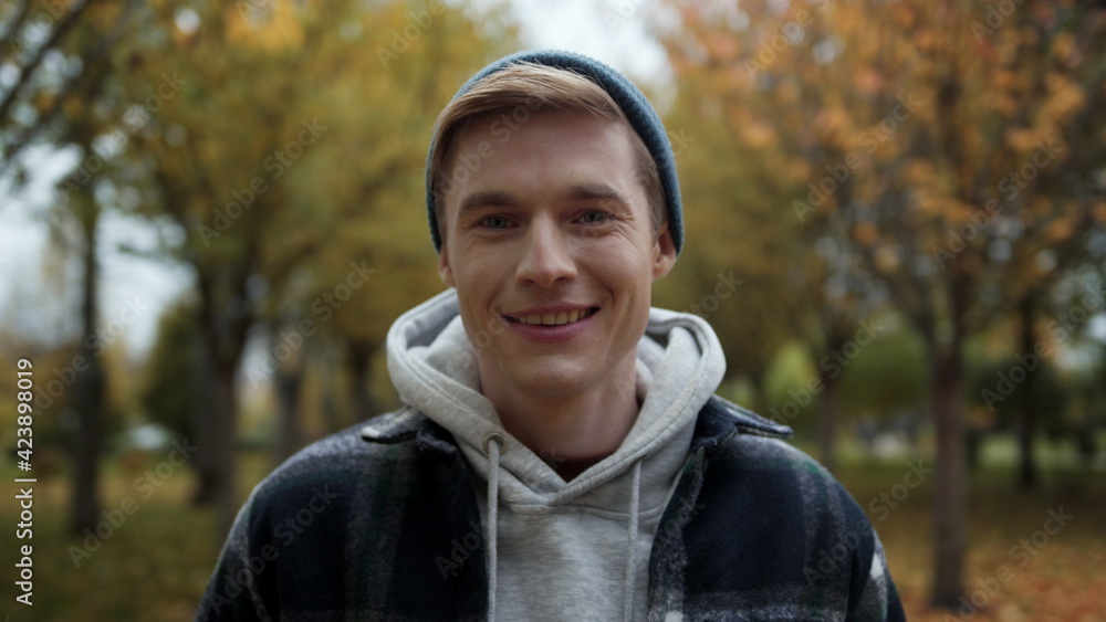 Cheerful handsome boy posing for camera in autumn park. Guy looking at camera. Cheerful handsome boy posing for camera in autumn park. Guy looking at camera.