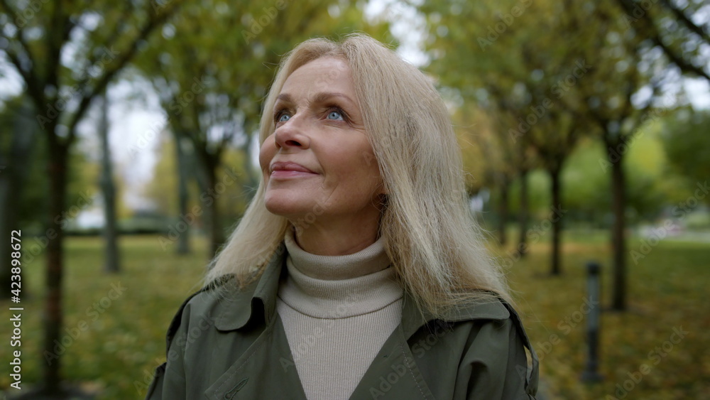 Portrait of romantic woman looking into sky through trees branches in park . Portrait of romantic woman looking into sky through trees branches in park .