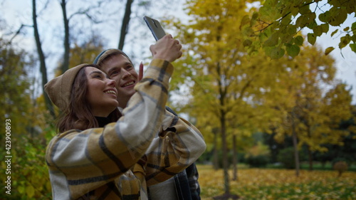 Cheerful young lovers making selfie video in autumn nature. Side shot.