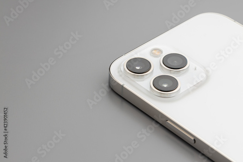 Close up of triple-lens camera of modern smartphone on gray background