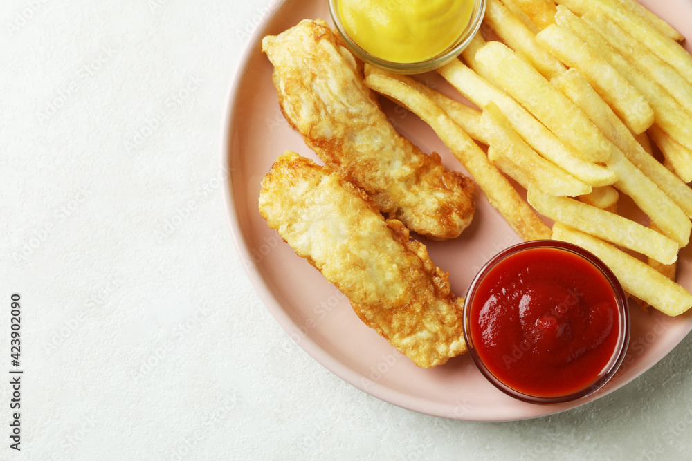 Plate with fried fish and chips, and sauces on white textured background Plate with fried fish and chips, and sauces on white textured background
